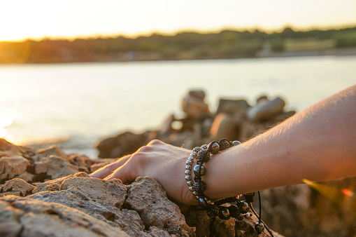 Hand with bracelets by the seaside. Sunset light.
