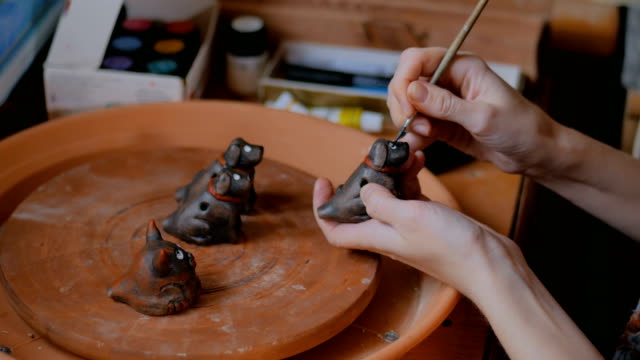 Professional potter painting ceramic souvenir penny whistle in pottery workshop