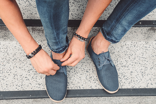Take a walk in my shoes - hands tying up shoelaces. Elegant blue shoes, jeans.