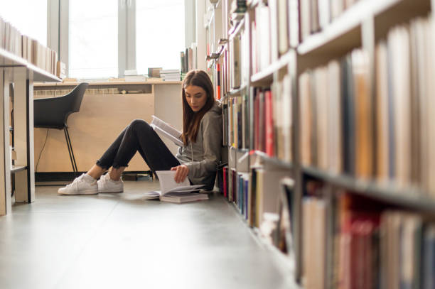 istock Beautiful female student reading in library 1138813825