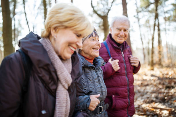 Active seniors on country walk Active seniors on country walk. Senior man and women walking together through forest trail on a cold winter day. grunewald berlin stock pictures, royalty-free photos & images