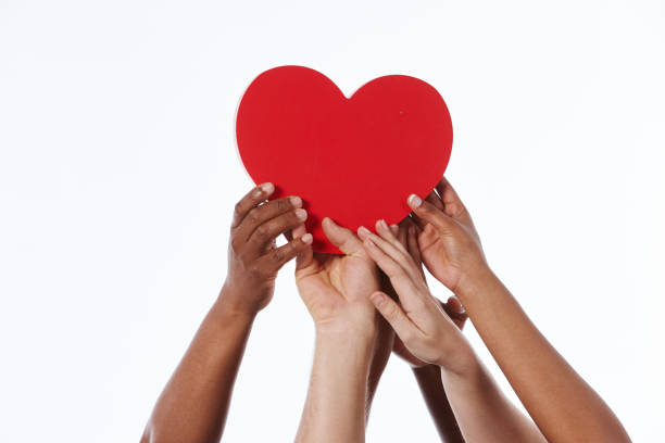 Mixed group of raised hands carefully carry red heart A large group of hands of various ethnic groups reach up to cradle a large red heart together. heart hands multicultural women stock pictures, royalty-free photos & images