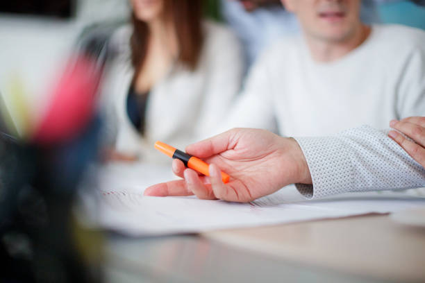 Hand pointing to data on the chart on a meeting and holding orange highlighter