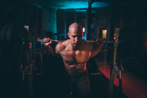 istock Shirtless man weightlifting in dark gym alone 1138820128