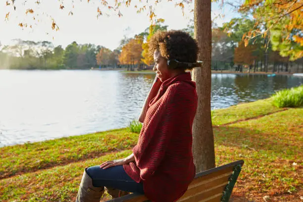 Woman listening music in the autumn park at sunset with headphones