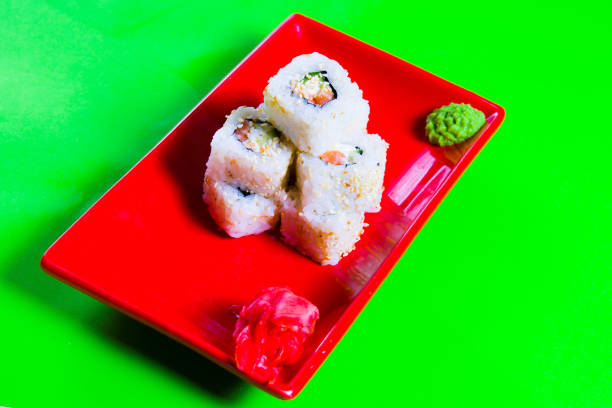 A portion of sushi on a red plate. green background.