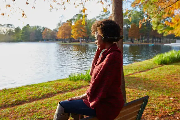 Woman listening music in the autumn park at sunset with headphones