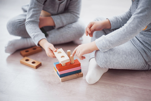 Children play with a toy designer on the floor of the children's room. Two kids playing with colorful blocks. Kindergarten educational games. Close up view.