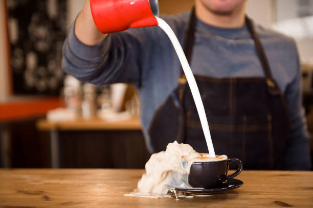 Close up barista pouring too much milk in coffee cup, making latte art