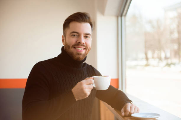 istock Attractive successful young businessman drinking coffee sitting at cafe table. 1138826912