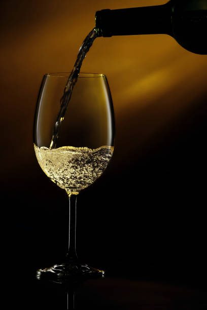 istock Pouring white wine from a bottle into a glass 1138828446