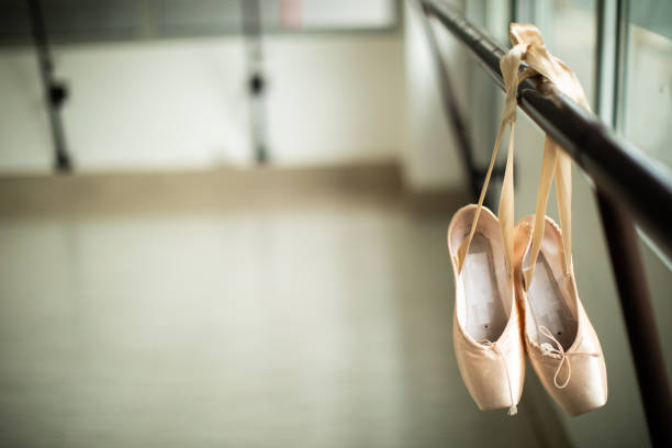 Ballet pumps hanging on barre Ballet shoes hanging on a barre in a ballet studio, close up ballet shoe stock pictures, royalty-free photos & images