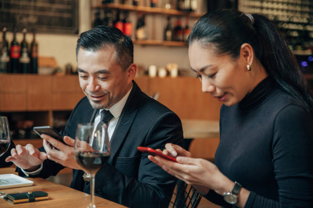 istock Man and woman using smart phones in restaurant 1138831087