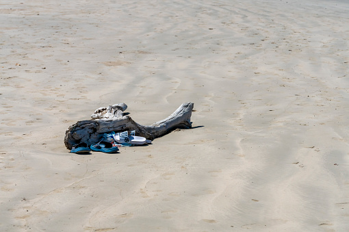 Log on the beach with flip flops left while swimming in the sea in Thailand.