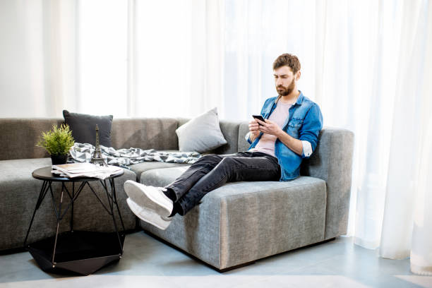 istock Man on the couch using phone at home 1138831236