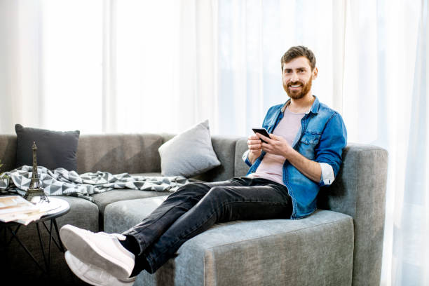 istock Man on the couch using phone at home 1138831244