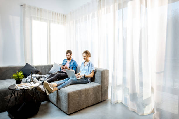 istock Couple sitting with gadgets on the couch at home 1138831267