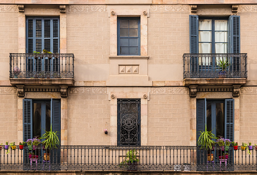 Several windows and balconies in a row on the facade of the urban historic building front view, Barcelona, Spain