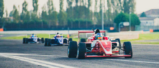 Three formula race cars on the race track Three formula race cars on the race track with a red single-seater leading the race. auto racing photos stock pictures, royalty-free photos & images
