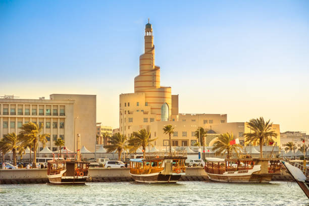 Dhow Harbor and Doha mosque Traditional wooden dhow anchored at Dhow Harbor in Doha Bay with spiral mosque and minaret in the background at sunset. View from Corniche promenade. Qatar, Middle East, Arabian Gulf. minaret photos stock pictures, royalty-free photos & images