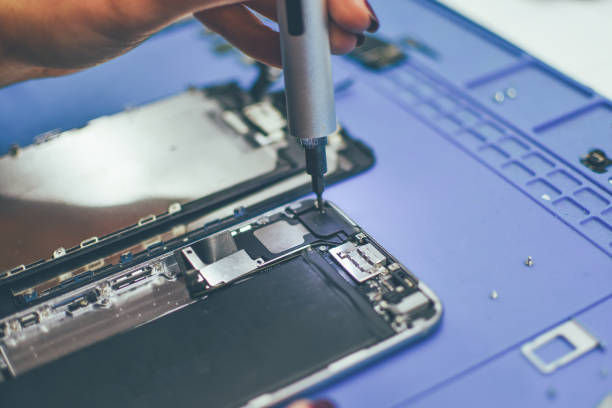 serviceman is repairing a damaged mobile phone - service electronics industry circuit board capacitor imagens e fotografias de stock