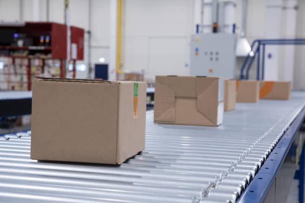 istock Packages delivery, packaging service and parcels transportation system concept, cardboard boxes on conveyor belt in warehouse 1138840217
