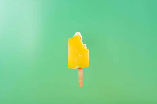 istock yellow popsicle with some bites on a light green background 1138840600