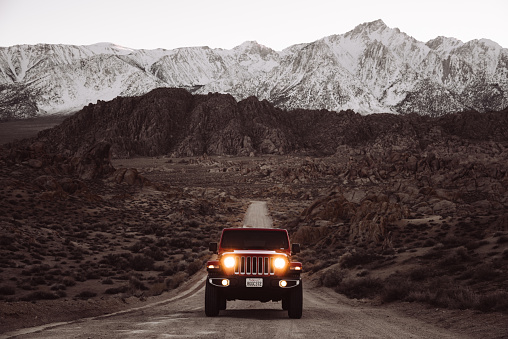 Lone Pine, California, United States - March 9, 2019: Photo of a Jeep Wrangler Sahara 2019 edition parked on a dirt road at the Alabama Hills close to the city of Lone Pine. It is the new wild offroad vehicle by Jeep. Headlights are on since the pic has been taken after the sunset.