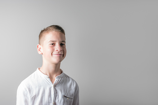 Smiling cute boy in a white shirt on bright background.