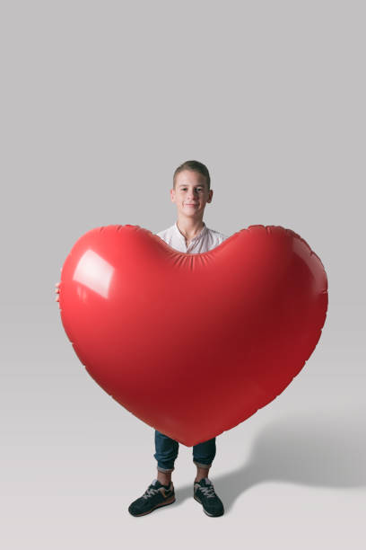 istock Cute boy with heart shaped balloon on bright background. Love concept. 1138841740