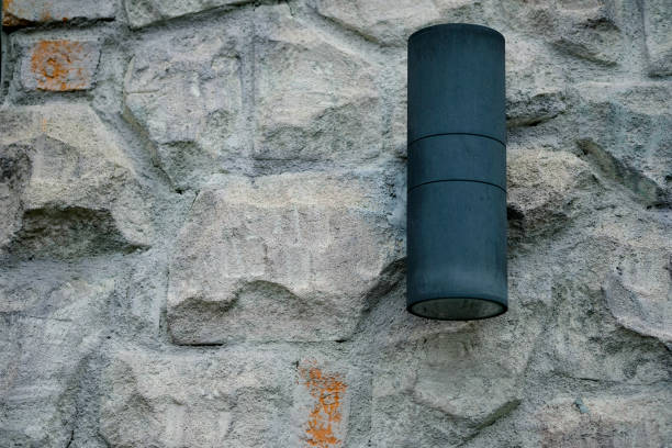 istock Cylinder black wall lamp on stone wall 1138842457