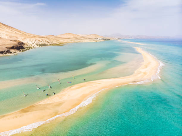 vista aerea della spiaggia nell'isola di fuerteventura con windsurfisti che imparano il windsurf in acqua turchese blu durante le vacanze estive, isole canarie dal drone - fuerteventura foto e immagini stock