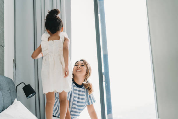 istock Mother and daughter playing together on the bed 1138846069