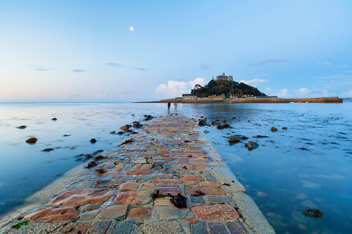 Two photographers, blurred and completely unrecognisable, prepare to shoot St Michael's Mount at dawn.