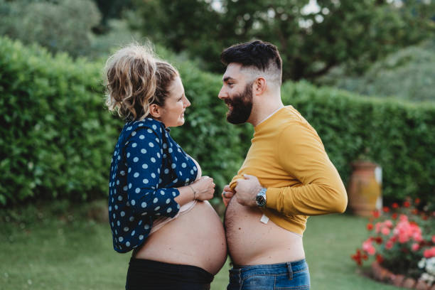 Young adult couple in love joking together Young adult couple in love joking together. She's pregnant and and he too pretends to be pregnant. irony stock pictures, royalty-free photos & images