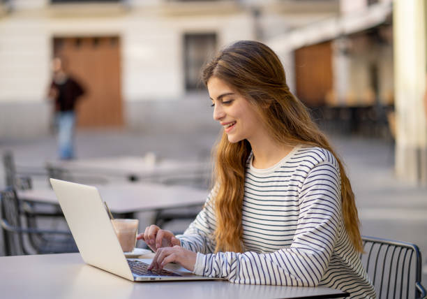 istock Pretty young cheerful woman drinking coffee, working or studying on her laptop computer outside at coffee shop. Feeling happy and satisfied. In entrepreneur, online education and technology concept. 1138852315