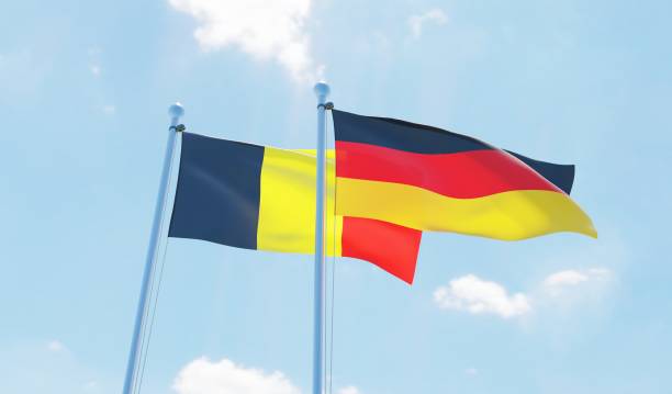istock Germany and Belgium, two flags waving against blue sky 1138859542