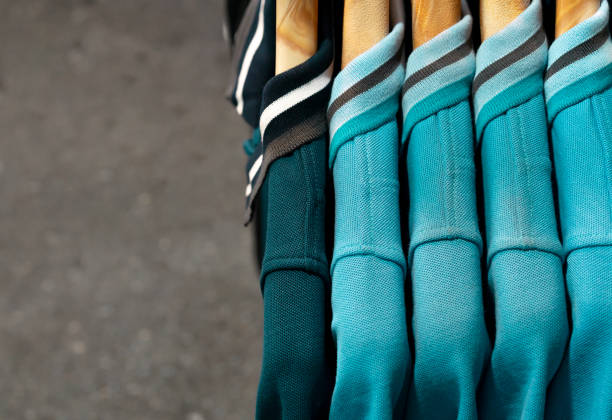 hängende unisex polo shirts auf dem display bei einem markt straßenverkäufer mit holzbügeln und kopierplatz - horizontal gestreiften vorhängen stock-fotos und bilder