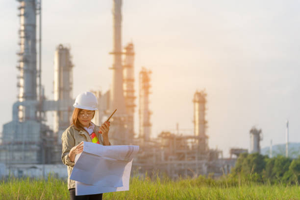 istock Engineer woman holding blueprint with radio for workers security control at power plant energy and petrochemical 1138863566