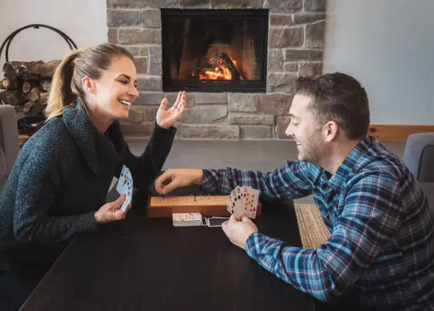 Couple playing cribbage in a warm home with fireplace