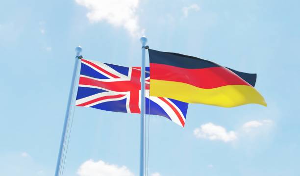 istock Germany and UK, two flags waving against blue sky 1138868195