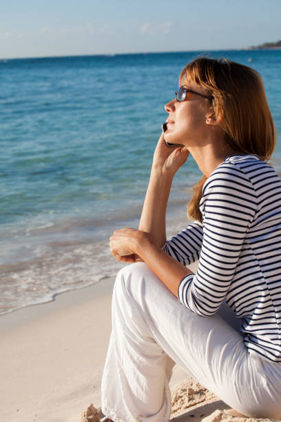 istock woman phoning on the beach 1138870593