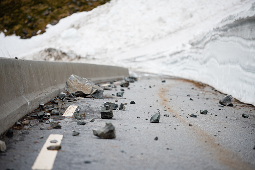 An Impassable mountain road is covered with rocks and snow.