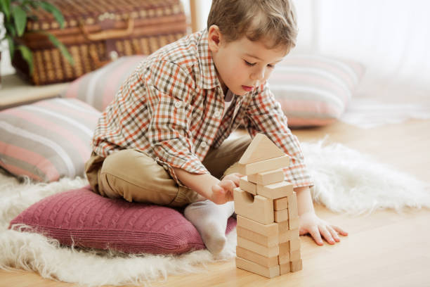 niño pequeño sentado en el suelo. bonito niño palying con cubos de madera en casa - cube baby child block fotografías e imágenes de stock