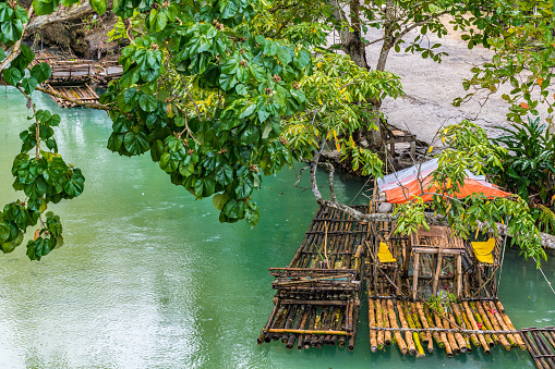 Empty bamboo rafts floating on a river. Dried bamboo canes are lashed together tightly to create this stable watercraft used for a scenic nature ride along a river.