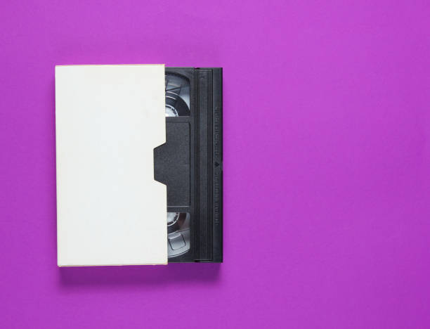 the videotape in a paper case on a purple background. pop culture attributes, minimalism. top view - video cassette tape imagens e fotografias de stock