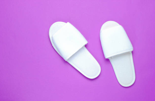 istock White hotel slippers on a purple background. Top view. Minimalism 1138884215