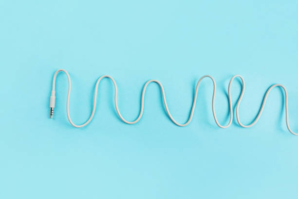 Grey waved audio jack cables on blue background closeup.