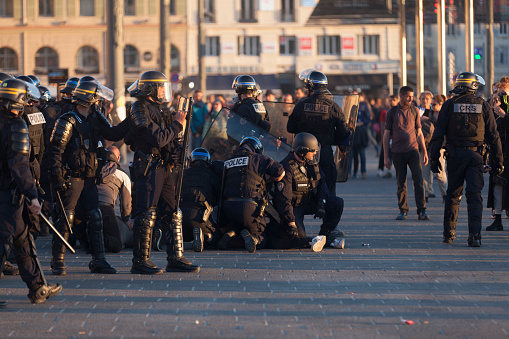 Marseille, France - March 23 2019: Policemen in riot gear holding to the ground a protester a little too agitated during a protest at the Vieux Port.