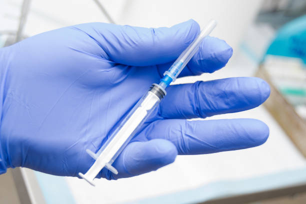 istock man holding a syringe in the hand with blue glove 1138886888